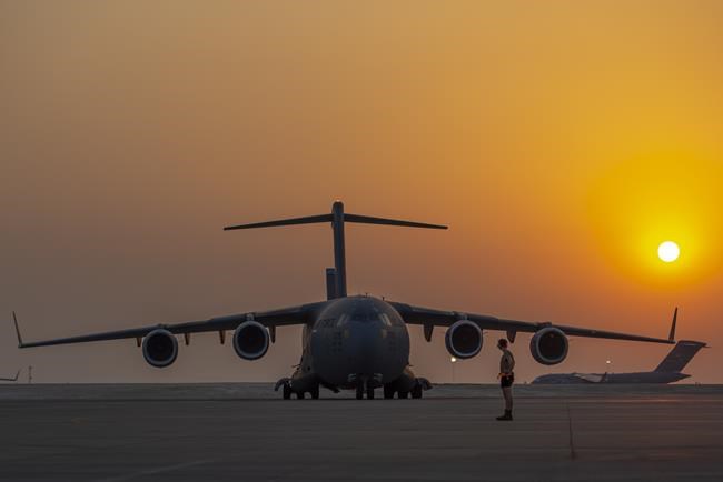In this image provided by the U.S. Air Force, a member from the 379th Air Expeditionary Wing prepares to marshal a C-17 Globemaster lll as another C-17 taxis onto the flightline Aug. 23, 2021, at Al Udeid Air Base, Qatar. (Airman 1st Class Kylie Barrow/U.S. Air Force via AP)