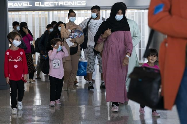 Families evacuated from Kabul, Afghanistan, walk through the terminal before boarding a bus after they arrived at Washington Dulles International Airport, in Chantilly, Va., on Wednesday, Aug. 25, 2021. (AP Photo/Jose Luis Magana)