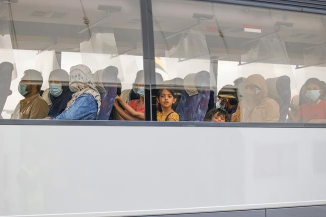People wait in a bus after disembarking from a Belgian chartered plane, as part of an evacuation from Afghanistan, upon arrival at Melsbroek Military Airport in Melsbroek, Belgium, Thursday, Aug. 26, 2021. (AP Photo/Olivier Matthys)