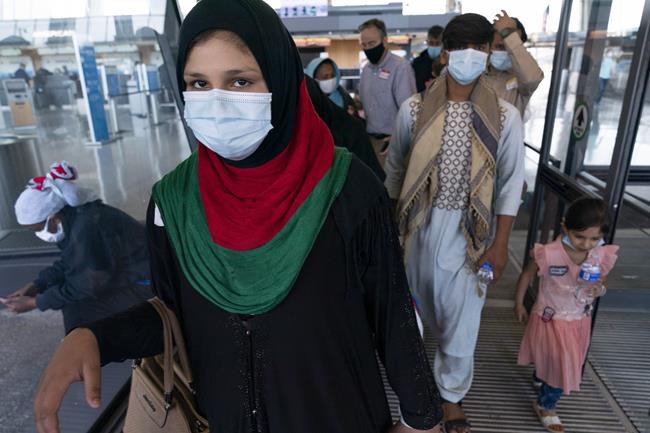Families evacuated from Kabul, Afghanistan, walk through the terminal before boarding a bus after they arrived at Washington Dulles International Airport, in Chantilly, Va., on Thursday, Aug. 26, 2021. (AP Photo/Jose Luis Magana)