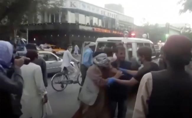In this image taken from video, people tend to a wounded person near the site of a deadly explosion outside the airport in Kabul, Afghanistan, Thursday, Aug. 26, 2021. Two suicide bombers and gunmen have targeted crowds massing near the Kabul airport, in the waning days of a massive airlift that has drawn thousands of people seeking to flee the Taliban takeover of Afghanistan. (Aśvaka News Agency via AP)