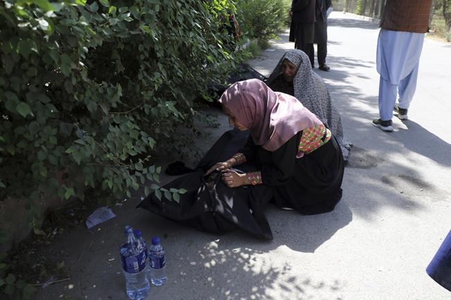 An Afghan woman tries to identify a dead body at a hospital in Kabul, Afghanistan, Friday, Aug. 27, 2021, a day after deadly attacks outside the airport. Two suicide bombers and gunmen attacked crowds of Afghans flocking to Kabul's airport Thursday, transforming a scene of desperation into one of horror in the waning days of an airlift for those fleeing the Taliban takeover. (AP Photo/Wali Sabawoon)