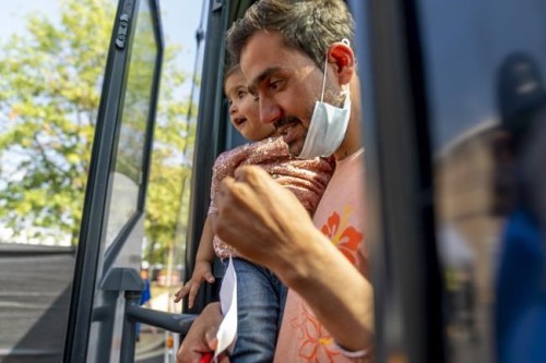 An Afghan man carries a girl as he and other refugees arrive at a processing center in Chantilly, Va., Monday, Aug. 23, 2021, after arriving on a flight at Dulles International Airport. (AP Photo/Andrew Harnik)