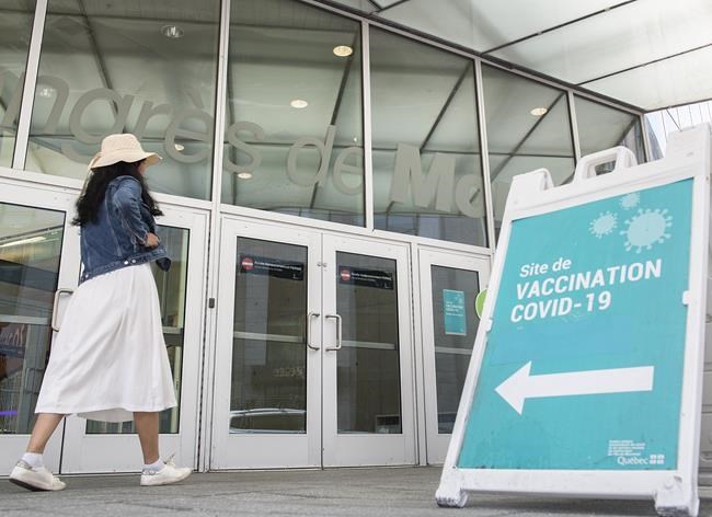 A woman walks by a COVID-19 vaccination sign in Montreal, Saturday, Aug. 21, 2021. THE CANADIAN PRESS/Graham Hughes