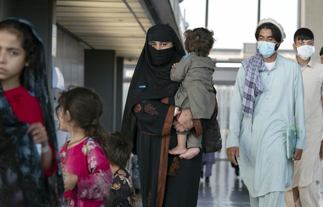 Families evacuated from Kabul, Afghanistan, walk through the terminal before boarding a bus after they arrived at Washington Dulles International Airport, in Chantilly, Va., on Friday, Aug. 27, 2021. (AP Photo/Jose Luis Magana)