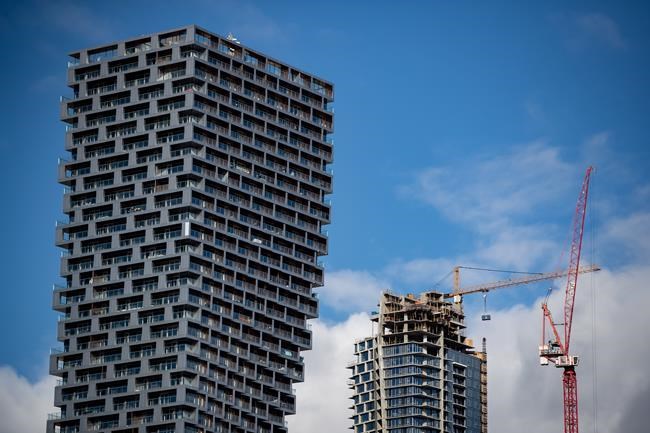 A crane is used to move a garbage bin to the upper floors of a condo tower under construction, in Vancouver, B.C., Tuesday, Feb. 16, 2021. THE CANADIAN PRESS/Darryl Dyck