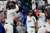 Chicago White Sox's Yasmani Grandal, right, celebrates with Eloy Jimenez, left, after hitting a three-run home run, next to Chicago Cubs catcher Austin Romine during the eighth inning of a baseball game in Chicago, Friday, Aug. 27, 2021. The White Sox won 17-13. (AP Photo/Nam Y. Huh)