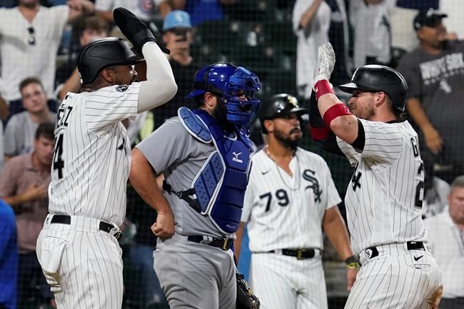 Chicago White Sox's Yasmani Grandal, right, celebrates with Eloy Jimenez, left, after hitting a three-run home run, next to Chicago Cubs catcher Austin Romine during the eighth inning of a baseball game in Chicago, Friday, Aug. 27, 2021. The White Sox won 17-13. (AP Photo/Nam Y. Huh)