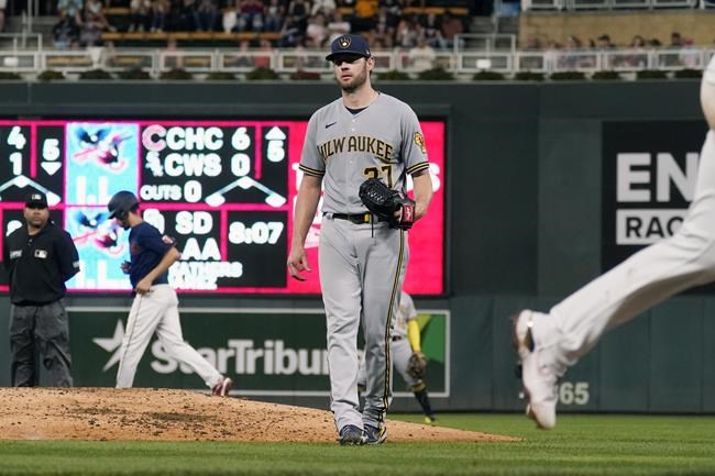 Milwaukee Brewers pitcher Adrian Houser, center, walks off the mound as Minnesota Twins' Brent Rooker, right, heads home on a bases-loaded walk off Houser of Twins' Luis Arraez as Andrelton Simmons, second from back left, heads to second base in the fourth inning of a baseball game Saturday, Aug. 28, 2021, in Minneapolis. (AP Photo/Jim Mone)