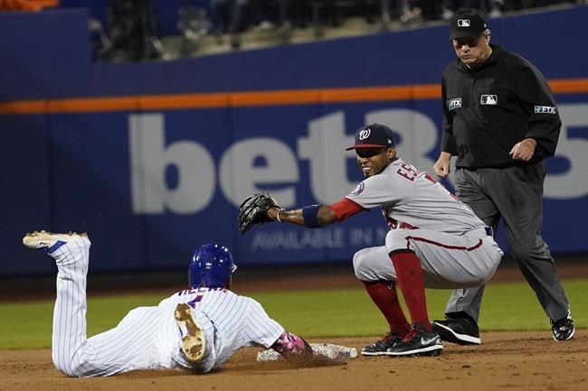 Washington Nationals shortstop Alcides Escobar, center, catches New York Mets' Jonathan Villar trying to steal during the third inning of a baseball game Saturday, Aug. 28, 2021, in New York. (AP Photo/Mary Altaffer)