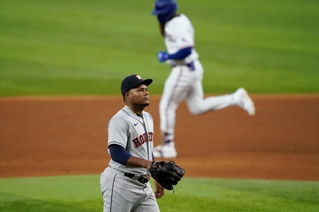 Houston Astros starting pitcher Framber Valdez, foreground, stands on the mound as Texas Rangers' Adolis Garcia, background, rounds the bases after hitting a solo home run in the sixth inning of a baseball game in Arlington, Texas, Saturday, Aug. 28, 2021. (AP Photo/Tony Gutierrez)
