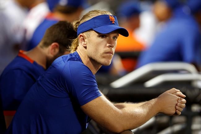 FILE - In this Aug. 14, 2021, file photo, New York Mets pitcher Noah Syndergaard watches play against the Los Angeles Dodgers during the first inning of a baseball game in New York. A person familiar with the situation tells The Associated Press that Syndergaard has tested positive for COVID-19. Syndergaard was scratched from a rehab start on Sunday, Aug. 29, 2021. The person spoke on condition of anonymity because the team has not disclosed the positive test. (AP Photo/Noah K. Murray, File)