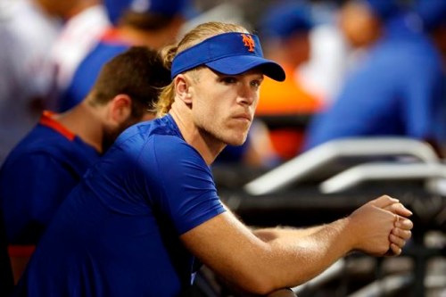 FILE - In this Aug. 14, 2021, file photo, New York Mets pitcher Noah Syndergaard watches play against the Los Angeles Dodgers during the first inning of a baseball game in New York. A person familiar with the situation tells The Associated Press that Syndergaard has tested positive for COVID-19. Syndergaard was scratched from a rehab start on Sunday, Aug. 29, 2021. The person spoke on condition of anonymity because the team has not disclosed the positive test. (AP Photo/Noah K. Murray, File)
