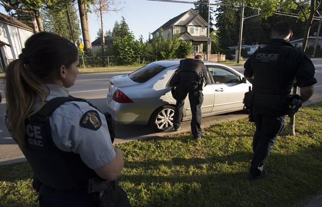 Members of the RCMP Gang Enforcement Team is silhouetted as he speaks to the occupants of a car during a stop in Surrey, B.C., Friday, May 31, 2019. Newly released figures suggest a steep erosion in public belief the RCMP is attentive to the needs of a diverse society. THE CANADIAN PRESS/Jonathan Hayward