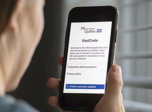 A woman looks at the Quebec government's new vaccine passport called VaxiCode on a phone in Montreal, Wednesday, Aug. 25, 2021. Quebecers are required starting today to show proof of vaccination to access businesses and events the government deems non-essential, such as restaurants, gyms and festivals. THE CANADIAN PRESS/Graham Hughes