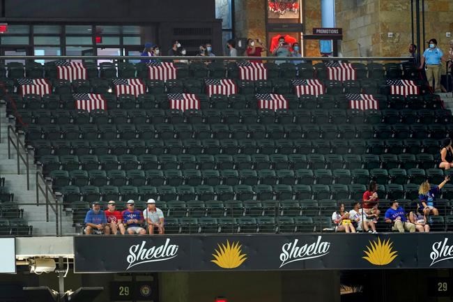 Thirteen U.S. flags sit draped over outfield seating at Globe Life Field during a baseball game between the Colorado Rockies and the Texas Rangers in Arlington, Texas, Tuesday, Aug. 31, 2021. A suicide bombing last week in Afghanistan killed 13 American service members and 169 Afghans. (AP Photo/Tony Gutierrez)