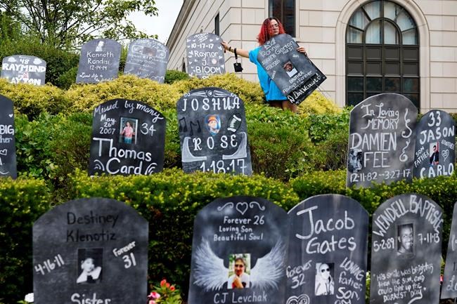 FILE - In this Aug. 9, 2021, file photo, Jayde Newton helps to set up cardboard gravestones with the names of victims of opioid abuse outside the courthouse where the Purdue Pharma bankruptcy is taking place in White Plains, N.Y. A federal bankruptcy judge is expected to rule Wednesday, Sept. 1, on whether to accept a settlement between OxyContin maker Purdue Pharma, the states and thousands of local governments over an opioid crisis that has killed a half-million Americans over the last two decades. (AP Photo/Seth Wenig, File)