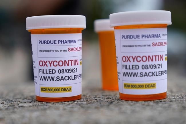 FILE - In this Aug. 9, 2021, file photo, fake pill bottles with messages about OxyContin maker Purdue Pharma are displayed during a protest outside the courthouse where the bankruptcy of the company is taking place in White Plains, N.Y. A federal bankruptcy judge is expected to rule Wednesday, Sept. 1, on whether to accept a settlement between Purdue Pharma, the states and thousands of local governments over an opioid crisis that has killed a half-million Americans over the last two decades. (AP Photo/Seth Wenig, File)