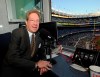 FILE - In this Sept. 25, 2009, file photo, New York Yankees broadcaster John Sterling sits in the booth before the Yankees' baseball game against the Boston Red Sox at Yankee Stadium in New York. Sterling was helped out of his flooding car by Spanish radio play-by-play man Rickie Ricardo on Wednesday night, Sept. 1, 2021, after Sterling got stuck trying to drive home after a game. Sterling and Ricardo both called New York's game at the Los Angeles Angels from Yankee Stadium because the radio crews have not resumed traveling with the team as part of COVID-19 protocols. (AP Photo/Bill Kostroun, File)