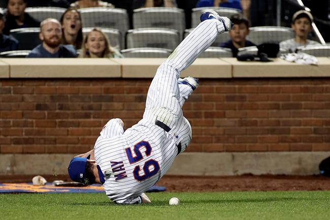 New York Mets pitcher Trevor May rolls over while chasing a foul ball hit by Miami Marlins' Jesus Aguilar during the eighth inning of a baseball game Thursday, Sept. 2, 2021, in New York. May did not make the catch. (AP Photo/Adam Hunger)