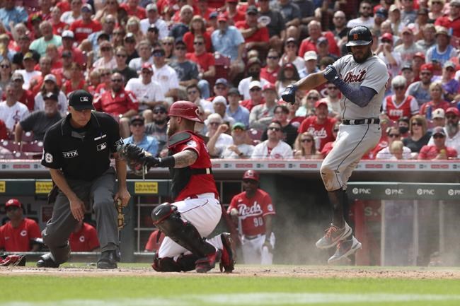 Detroit Tigers' Jeimer Candelario, right, leaps in the air after scoring on a sacrifice fly off the bat of Eric Haase, as Cincinnati Reds catcher Tucker Barnhart, center, looks for the call from home plate umpire Dan Iassogna during the sixth inning of a baseball game, Sunday, Sept. 5, 2021, in Cincinnati. (AP Photo/Gary Landers)
