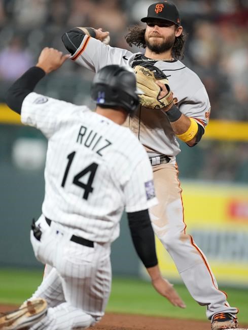San Francisco Giants shortstop Brandon Crawford, back, throws to first base after putting out Colorado Rockies' Rio Ruiz at second base on the front end of a double play hit into by Raimel Tapia to end the fifth inning of a baseball game Tuesday, Sept. 7, 2021, in Denver. (AP Photo/David Zalubowski)