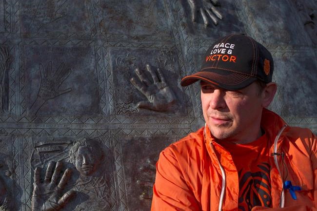 Former NHLer Theo Fleury stands in front of a child abuse monument as he begins