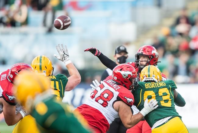 Calgary Stampeders quarterback Bo Levi Mitchell (19) gets a pass out under pressure from Edmonton Elks' Kwaku Boateng (93) and Jake Ceresna (94) as Stampeders' Justin Lawrence (68) blocks during first half CFL action in Edmonton, Alta., on Saturday September 11, 2021. THE CANADIAN PRESS/Amber Bracken