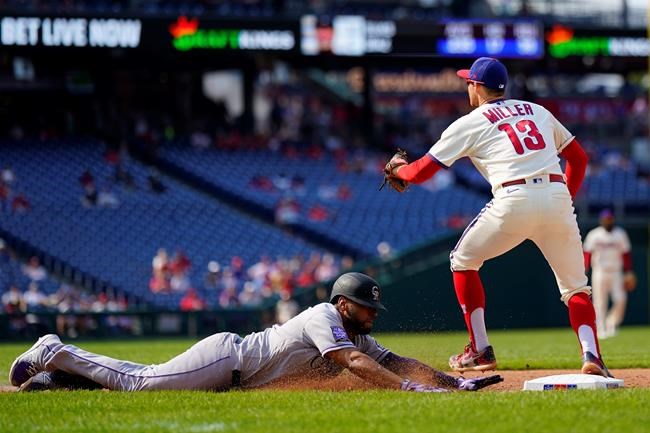 Colorado Rockies' Elias Diaz, left, slides into first base for a single past Philadelphia Phillies first baseman Brad Miller during the seventh inning of a baseball game, Sunday, Sept. 12, 2021, in Philadelphia. (AP Photo/Matt Slocum)