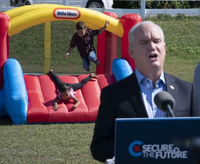 Children play on a bouncy castle as Conservative party Leader Erin O'Toole delivers remarks at a campaign stop in Carp, Ont., on Monday, Sept. 13, 2021. THE CANADIAN PRESS/Adrian Wyld