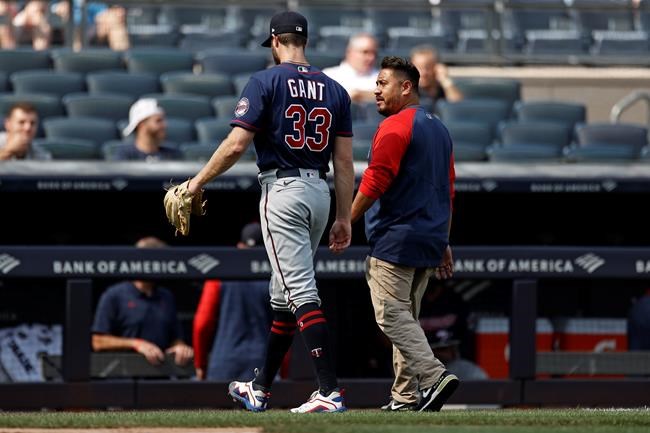 ADDS NAME OF HEAD ATHLETIC TRAINER MICHAEL SALAZAR - Minnesota Twins pitcher John Gant (33) walks off the field with Twins head athletic trainer Michael Salazar after being taken out of a baseball game against the New York Yankees during the first inning Monday, Sept. 13, 2021, in New York. (AP Photo/Adam Hunger)
