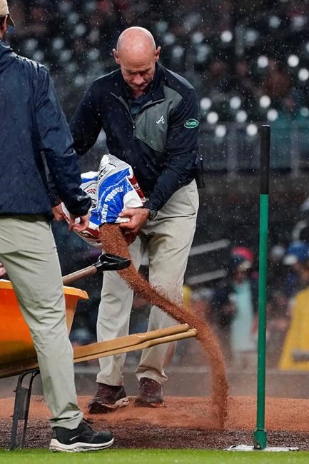 Atlanta Braves field director Ed Magan works to dry the pitcher's mound before the third inning of the team's baseball game against the Colorado Rockies on Wednesday, Sept. 15, 2021, in Atlanta. (AP Photo/John Bazemore)