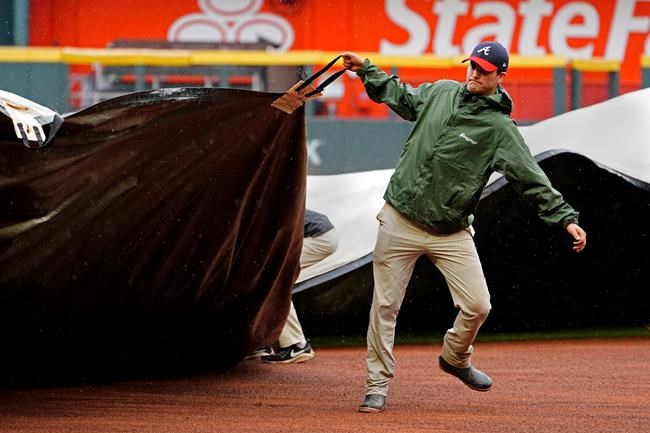 Members of the Atlanta Braves grounds crew work to cover the infield before a baseball game between Atlanta Braves and Colorado Rockies was cancelled because of rain Thursday, Sept. 16, 2021, in Atlanta. (AP Photo/John Bazemore)