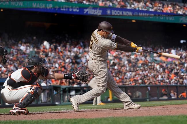 San Diego Padres' Manny Machado hits a two-run single in front of San Francisco Giants catcher Curt Casali during the eighth inning of a baseball game in San Francisco, Thursday, Sept. 16, 2021. (AP Photo/Jeff Chiu)