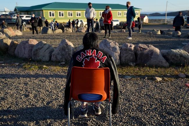 Liberal Leader Justin Trudeau's jacket is worn by an elder after Trudeau gave it to her to warm up during a campaign stop in Iqaluit on Monday, Aug. 30, 2021. Nearly 5.8 million Canadians voted in advance polls, says Elections Canada, but residents in nine communities in Nunavut will have to wait until Monday to cast their ballot. THE CANADIAN PRESS/Nathan Denette