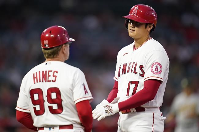 Los Angeles Angels designated hitter Shohei Ohtani (17) talks with first base coach Bruce Hines (99) at first base during the first inning of a baseball game against the Oakland Athletics Friday, Sept. 17, 2021, in Anaheim, Calif. (AP Photo/Ashley Landis)