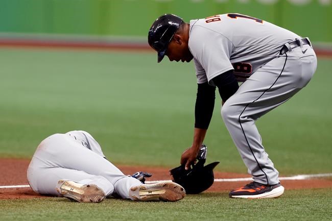Detroit Tigers' Derek Hill lays on the field as first base coach Kimera Bartee leans over during the fifth inning of a baseball game against the Tampa Bay Rays Saturday, Sept. 18, 2021, in St. Petersburg, Fla. (AP Photo/Scott Audette)