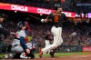San Francisco Giants' Curt Casali (2) hits a two-run single in front of Atlanta Braves catcher Travis d'Arnaud during the fourth inning of a baseball game in San Francisco, Saturday, Sept. 18, 2021. (AP Photo/Jeff Chiu)