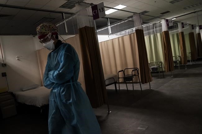 FILE - In this Wednesday, Feb. 10, 2021 file photo, traveling registered nurse Patricia Carrete, of El Paso, Texas, walks down the hallways during a night shift at a field hospital set up to handle a surge of COVID-19 patients in Cranston, R.I. (AP Photo/David Goldman, File)