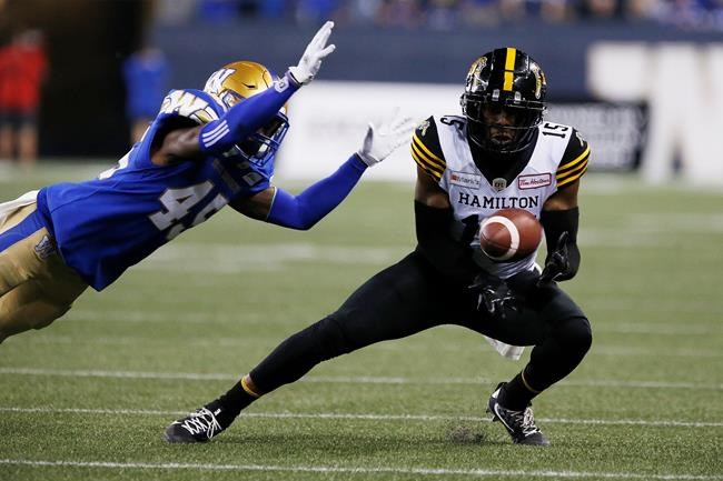 Hamilton Tiger-Cats' Marcus Tucker (15) makes the catch as Winnipeg Blue Bombers' DeAundre Alford (45) defends during second half CFL action in Winnipeg Thursday, August 5, 2021. THE CANADIAN PRESS/John Woods