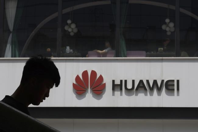 FILE - In this Thursday, May 16, 2019 file photo, a man is silhouetted near the Huawei logo in Beijing. Lithuanian cybersecurity authorities are urging the country’s governmental agencies to abandon the use of Chinese smartphone brands. Lithuania’s National Cyber Security Center said Tuesday, Sept. 21, 2021 it found four major cybersecurity risks for devices made by Huawei and Xiaomi. (AP Photo/Ng Han Guan, file)