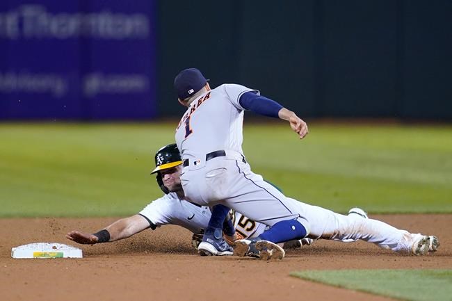 Houston Astros shortstop Carlos Correa, top, tags out Oakland Athletics' Seth Brown who was trying to steal second base during the sixth inning of a baseball game in Oakland, Calif., Friday, Sept. 24, 2021. (AP Photo/Jeff Chiu)