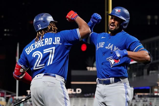 Toronto Blue Jays Marcus Semien, right, celebrates his solo home run off Minnesota Twins pitcher Bailey Ober with Vladimir Guerrero Jr. in the sixth inning of a baseball game, Friday, Sept. 24, 2021, in Minneapolis. THE CANADIAN PRESS/AP, Jim Mone
