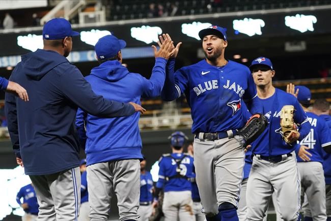 Toronto Blue Jays centerfielder George Springer, center, and other players go through the celebration line after the Blue Jays' 6-1 win over the Minnesota Twins in a baseball game, Saturday, Sept. 25, 2021, in Minneapolis. Springer hit a two-run home run in the game. (AP Photo/Jim Mone)