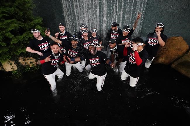 The Atlanta Braves players celebrate in a fountain after a baseball game against the Philadelphia Phillies, Thursday, Sept. 30, 2021, in Atlanta. The Atlanta Braves clinched the NL East title against the Philadelphia Phillies. (AP Photo/John Bazemore)