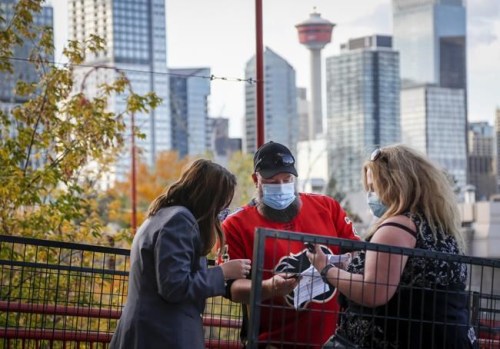 Calgary Flames fans have their COVID-19 vaccination proof checked before entering the Saddledome for pre-season NHL hockey action in Calgary, Alta., Sunday, Sept. 26, 2021. Canadians overwhelmingly support the idea of requiring vaccine passports to gain admittance to public places such as restaurants, bars and gyms, a new poll suggests. THE CANADIAN PRESS/Jeff McIntosh