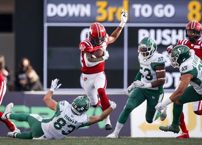 Saskatchewan Roughriders' Jake Harty, left, grabs for Calgary Stampeders' Malik Henry during first half CFL football action in Calgary, Saturday, Oct. 2, 2021.THE CANADIAN PRESS/Jeff McIntosh