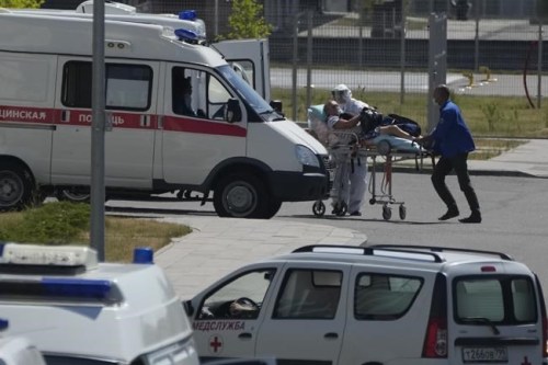 FILE - In this Monday, July 12, 2021 filer, a medical worker wearing protective gear escorts a man, suspected of having coronavirus, at a hospital in Kommunarka, outside Moscow, Russia. Russia has reported a record daily death toll from COVID-19. It's the fifth time in a week that deaths have hit a new high in the country. The national coronavirus task force said Sunday, Oct. 3, 2021 that 890 deaths were recorded over the past day. That exceeds the 887 reported on Friday. (AP Photo/Pavel Golovkin, File)