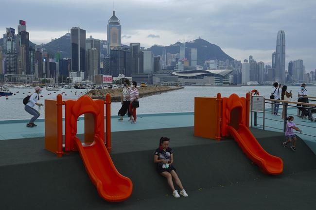 People walk at a waterfront park against Victoria Habour as Tropical Storm Kompasu approaches Hong Kong Tuesday, Oct. 12, 2021. The Hong Kong Observatory said it will consider issuing the number 8 signal between 4pm and 6pm on Tuesday as severe Tropical Storm Kompasu edges closer to the city. (AP Photo/Vincent Yu)