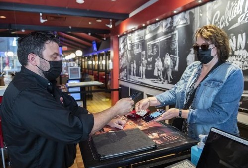 Jimmy Staveris, manager of Dunn's Famous restaurant, scans the COVID-19 QR code of a customer in Montreal, Wednesday, September 1, 2021. Vaccine passports are emerging as the latest pandemic minefield for restaurant workers in Canada, one riddled with verbal abuse, sexual harassment, racism and forged documents. THE CANADIAN PRESS/Graham Hughes